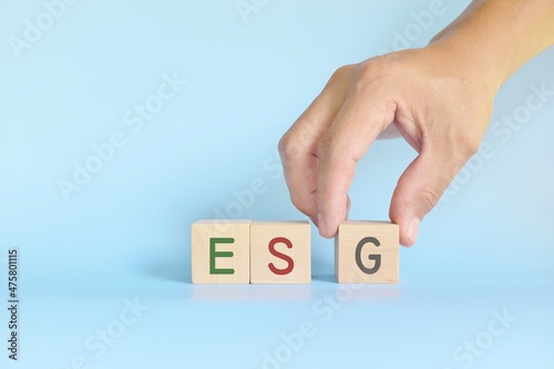 Hand stacking ESG or Environmental, Social and Governance wooden blocks. Support sustainable and responsible business concept.