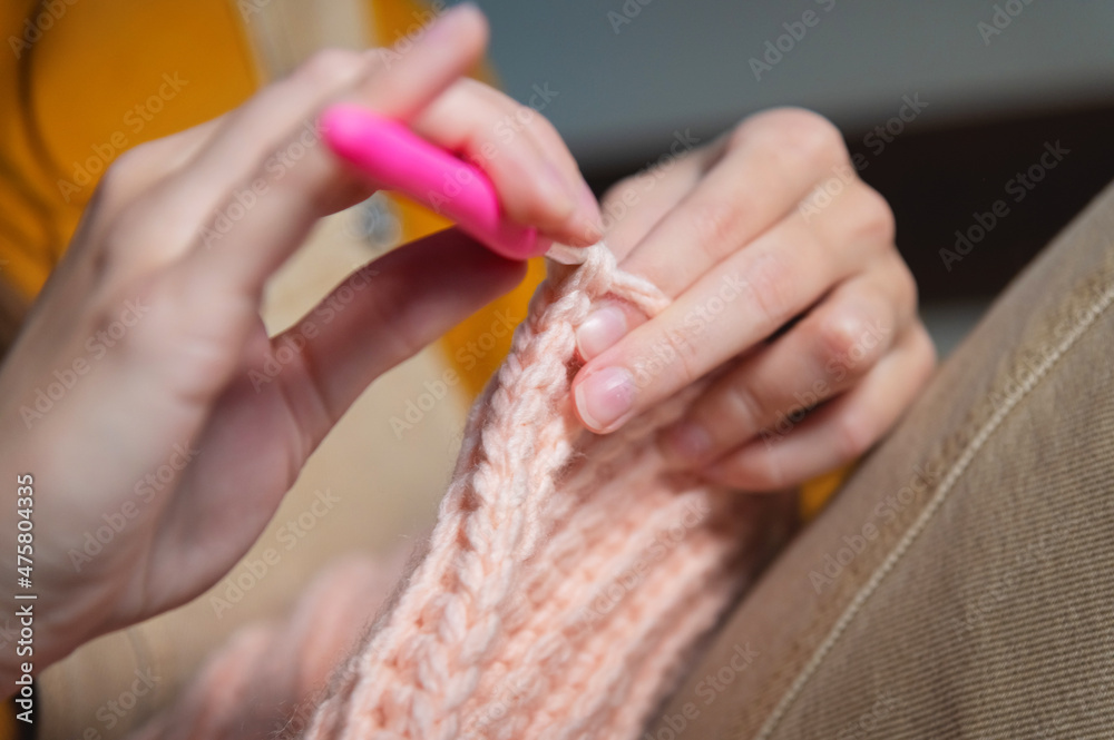 Fototapeta premium Close-up of young female hands of a Caucasian girl doing crochet, shows how to knit correctly. Shallow depth of field. high dynamic range.