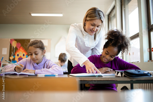 School teacher and students working together on their test in classroom.