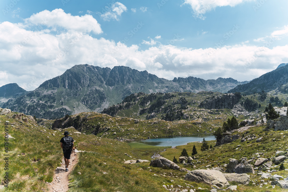 man is walking in the middle of the mountains with a lake in the background