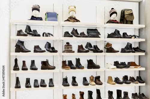 Shoes and accessories on the shelves in the store. Collection of the autumn-winter season. Hats, bags and boots. Front view.