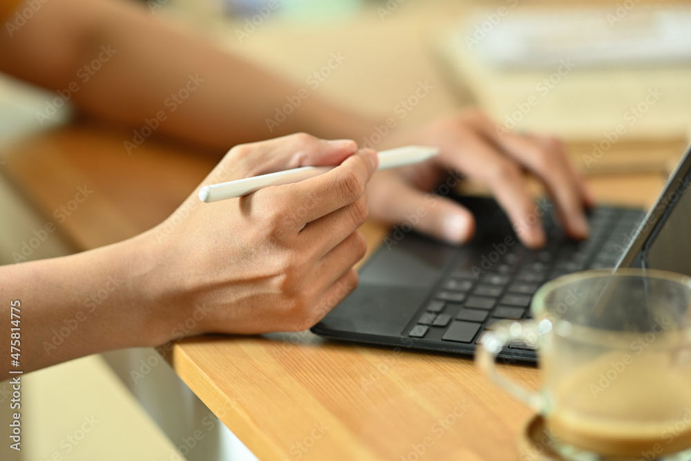 Cropped image of a young freelance man using a digital tablet and stylus pen at the wooden working desk. Cropped image of a young freelance man using a digital tablet and stylus pen at the wooden working desk.