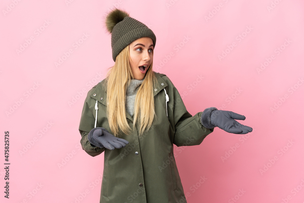 Young woman with winter hat isolated on pink background with surprise expression while looking side Young woman with winter hat isolated on pink background with surprise expression while looking side