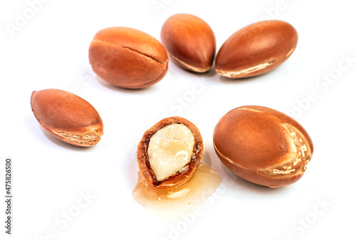 Argan nuts on an isolated white background. Chopped argan nut with a drop of oil. Whole and half Moroccan Argania Spinosa seeds for the production of oil