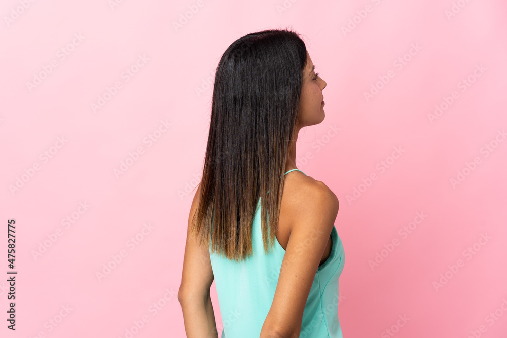 Caucasian girl isolated on pink background in back position and looking back