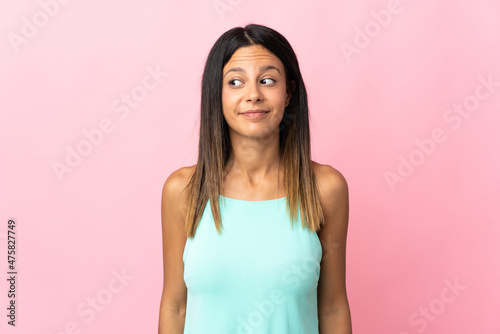 Caucasian girl isolated on pink background making doubts gesture looking side