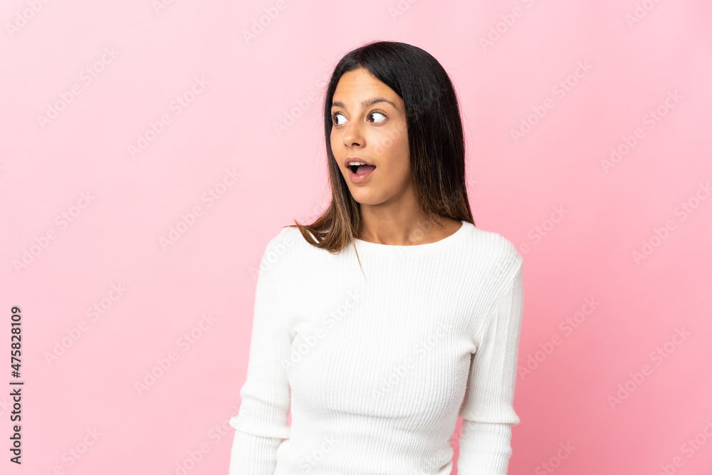 Caucasian girl isolated on pink background doing surprise gesture while looking to the side Caucasian girl isolated on pink background doing surprise gesture while looking to the side