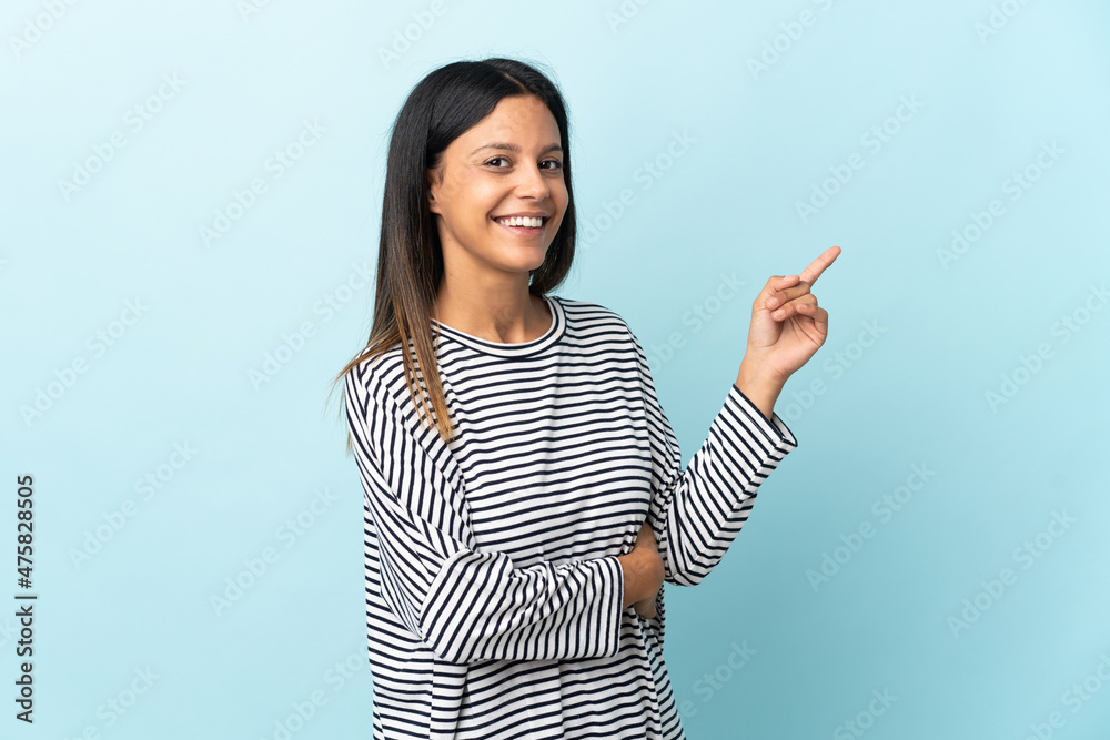 Caucasian girl isolated on blue background pointing finger to the side