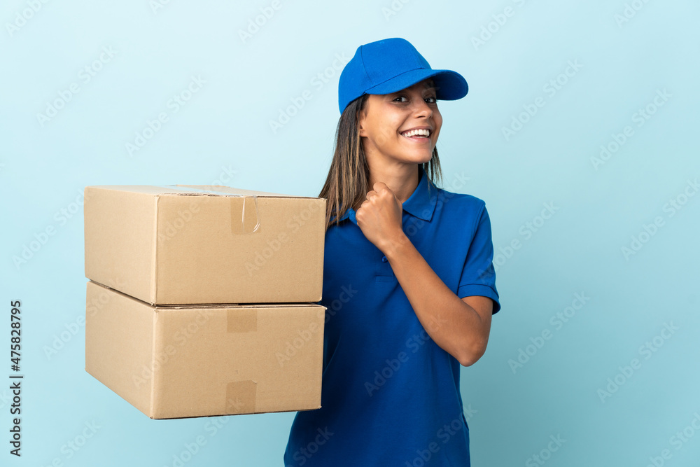Young delivery woman isolated on blue background celebrating a victory Young delivery woman isolated on blue background celebrating a victory