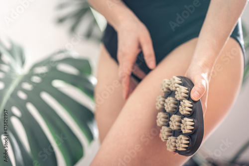 Body massage brush in female hands on a blurred background.
