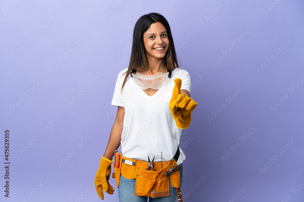 Young electrician woman isolated on purple background showing and lifting a finger Young electrician woman isolated on purple background showing and lifting a finger