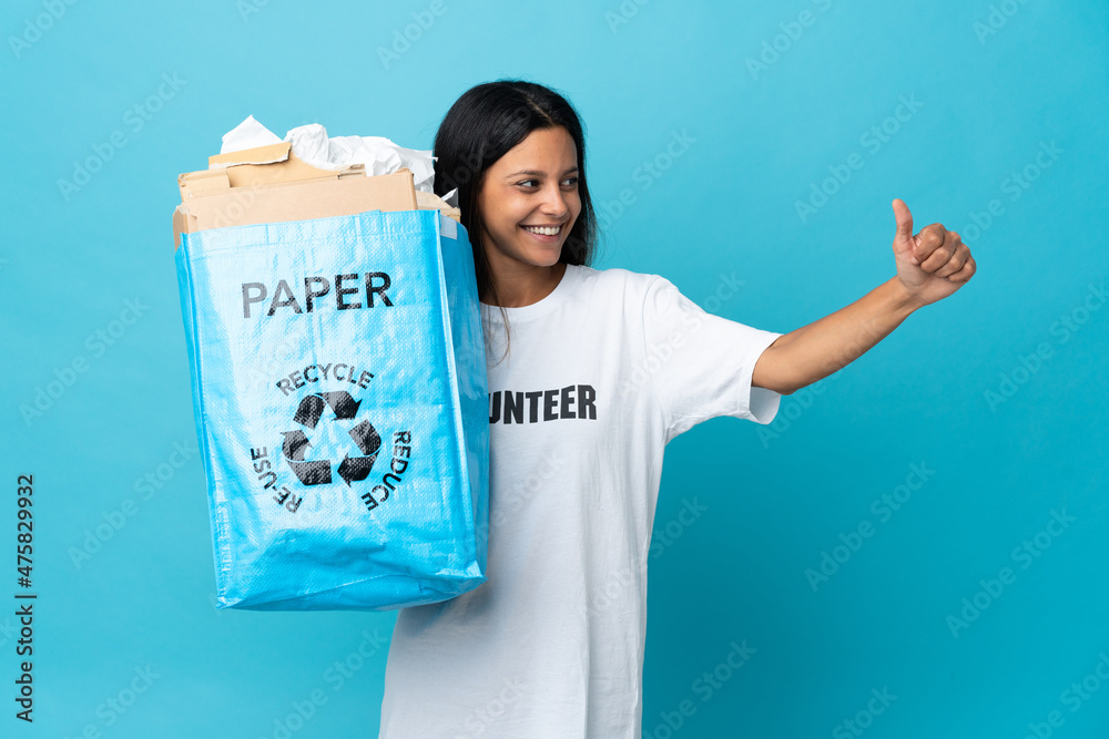 Young woman holding a recycling bag full of paper giving a thumbs up gesture Young woman holding a recycling bag full of paper giving a thumbs up gesture