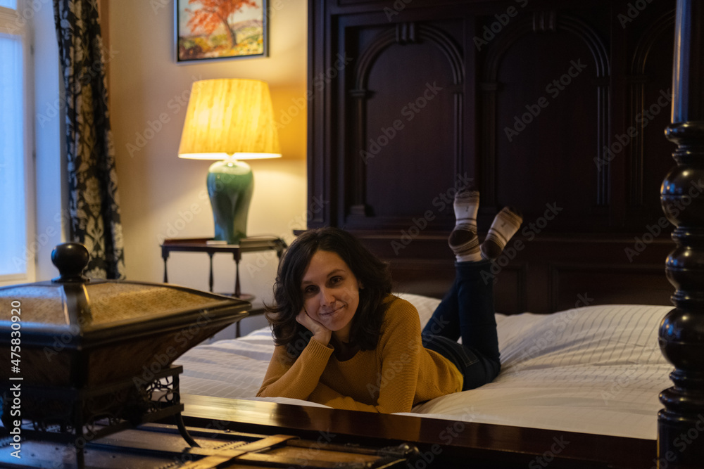 Girl smiling and laying on a canopy bed at night Girl smiling and laying on a canopy bed at night