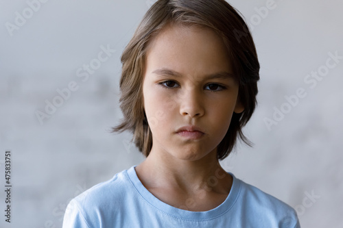 Head shot portrait of angry nervous small teenage child boy, feeling abused after quarrel. Anxious stressed little preteen adopted kid showing negative emotions, suffering from communication problems.