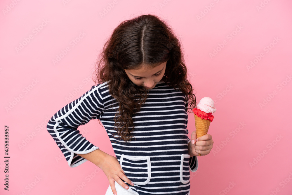 Little caucasian girl holding an ice cream isolated on pink background suffering from backache for having made an effort Little caucasian girl holding an ice cream isolated on pink background suffering from backache for having made an effort