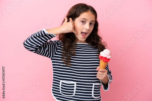 Little caucasian girl holding an ice cream isolated on pink background making phone gesture. Call me back sign