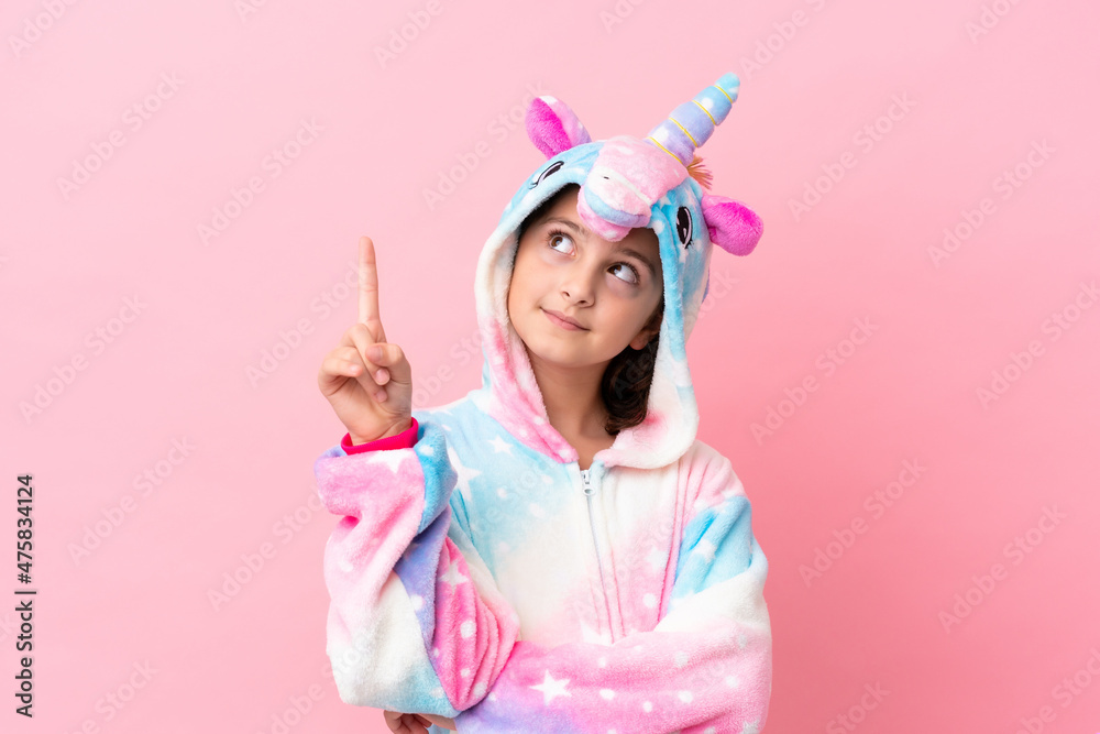Little caucasian woman wearing a unicorn pajama isolated on pink background pointing up a great idea Little caucasian woman wearing a unicorn pajama isolated on pink background pointing up a great idea