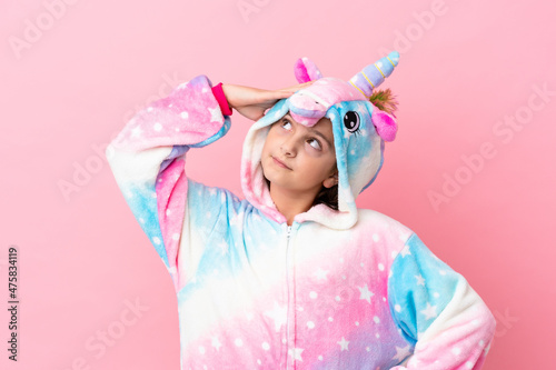 Little caucasian woman wearing a unicorn pajama isolated on pink background smiling a lot