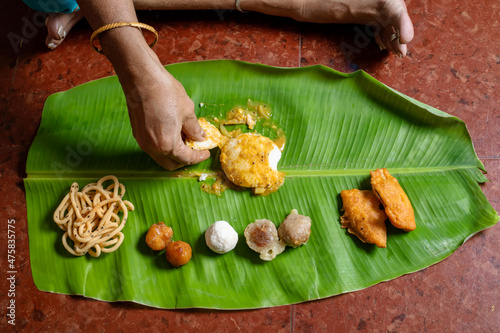 Woman eating traditional food served on banana leaf on Indian festival day.