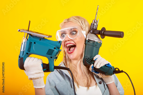 Beautiful girl with an electric drill and an electric jigsaw.