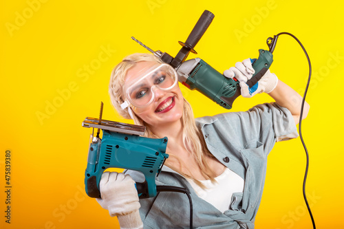 Beautiful girl with an electric drill and an electric jigsaw.