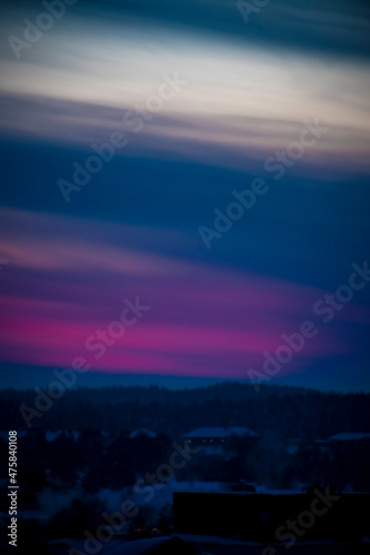 Blurred colorful sunset sky in Lithuania. Bright pink clouds illuminated by setting sun, dark forest in winter. No selective focus, defocused background.