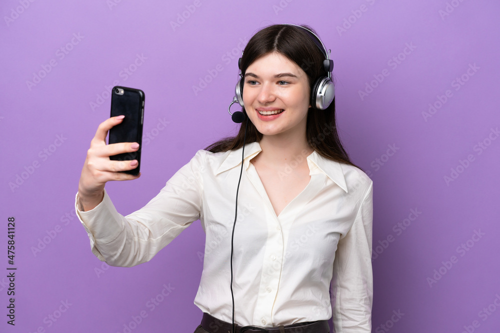 Telemarketer Russian woman working with a headset isolated on purple background making a selfie