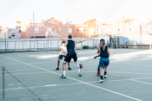 Four friends playing basketball together in an outdoors court © Samuel Perales