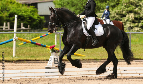 Foto Dressage horse Friesian with rider galloping in a tournament..