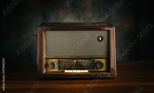 Front view, retro old fashioned radio receiver on wooden table on black background.