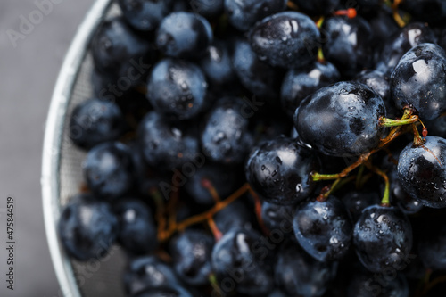 Sweet black grapes in a metal bowl on a dark textured background. photo