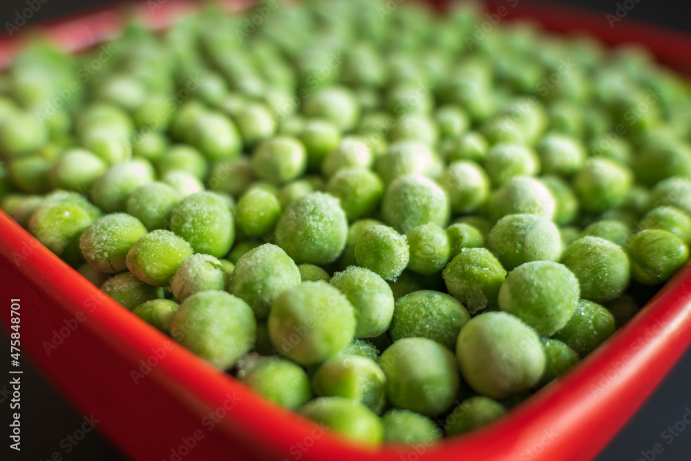 frozen frosty green peas in red ceramic bowl closeup frozen frosty green peas in red ceramic bowl closeup