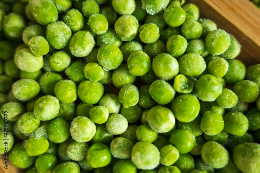 frozen frosty green peas on wooden plate closeup frozen frosty green peas on wooden plate closeup