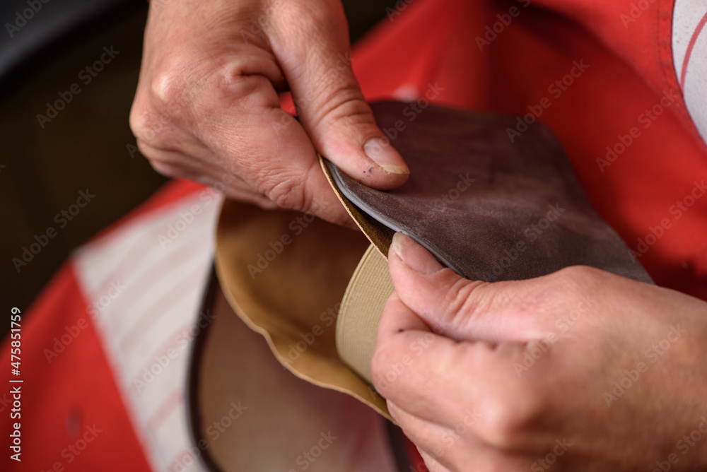 Shoemaker hands sewing the lining to the handmade leather shoe in workshop. Manufacturing of craft shoes. Small business concept.