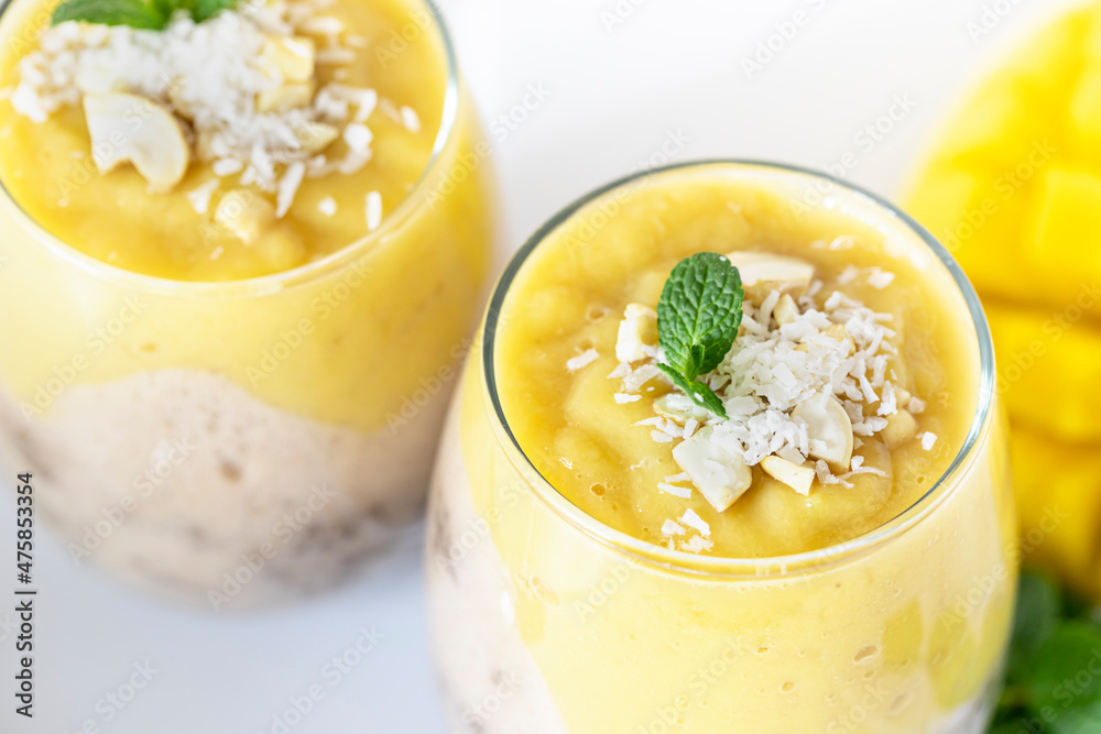 Delicious mango and chia pudding in a glass on the white ceramic tile table close up. Healthy morning breakfast concept