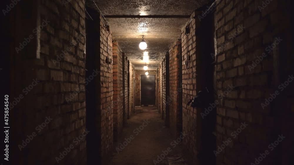 walking through a gloomy long basement with lanterns tunnel closing doors brick walls inspiring despair and horror. High quality 4k footage