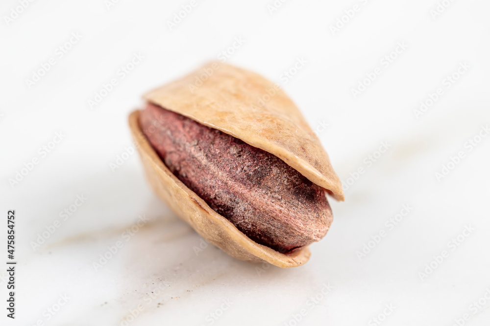 Pile of pistachios in the peel close-up. Pistachio isolated on marble background. Pile of pistachios in the peel close-up. Pistachio isolated on marble background.