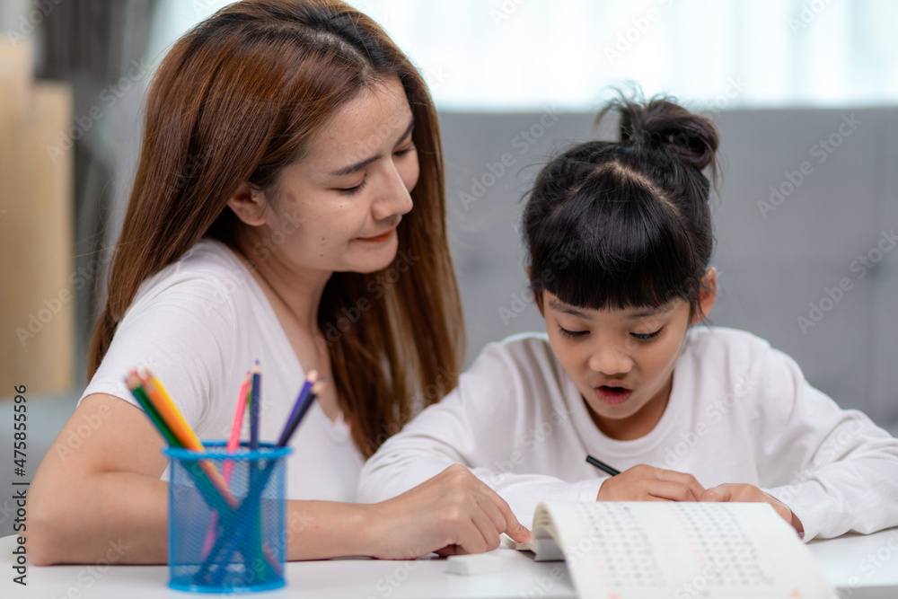 Beautiful Asian woman helping her daughter with homework at home. Beautiful Asian woman helping her daughter with homework at home.
