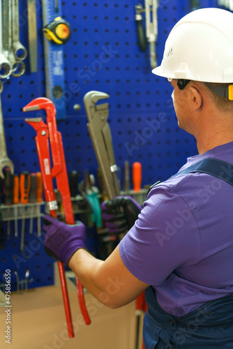 a white man in overalls and a purple shirt chooses a tool