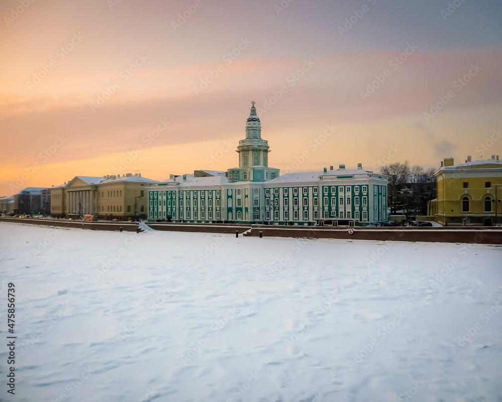 Obraz premium Kunstkamera in Sankt Petersburg, Russland – historisches Barockgebäude am Ufer der Newa im Winter bei Sonnenuntergang, verschneite Landschaft und beeindruckende Architektur der UNESCO-Welterbestadt