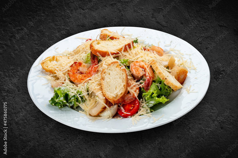 Caesar salad with seafood, egg and fresh vegetables. Isolated on a black background