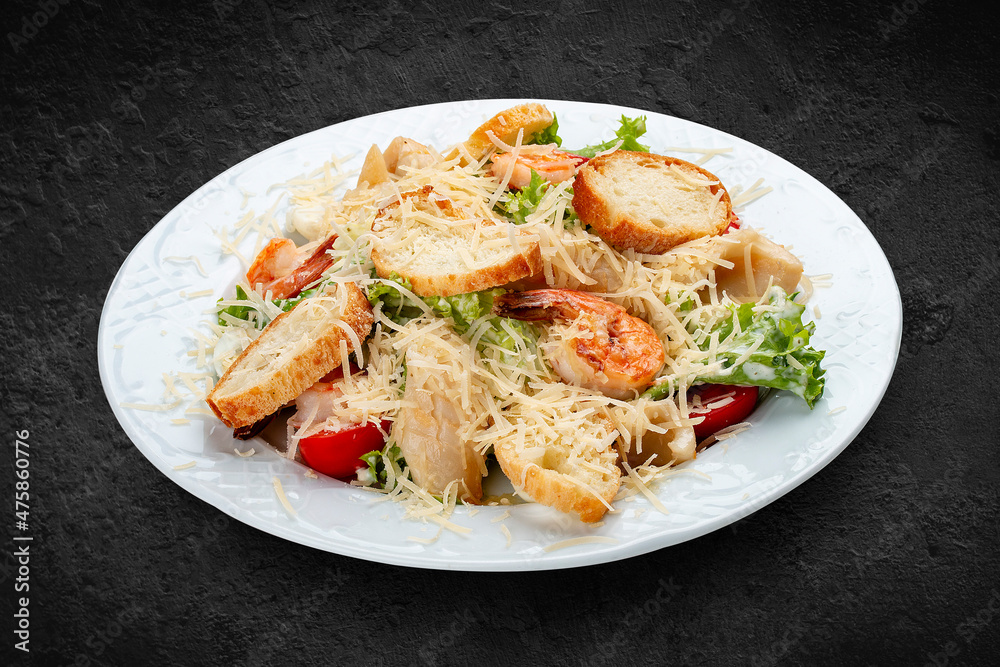 Caesar salad with seafood, egg and fresh vegetables. Isolated on a black background Caesar salad with seafood, egg and fresh vegetables. Isolated on a black background