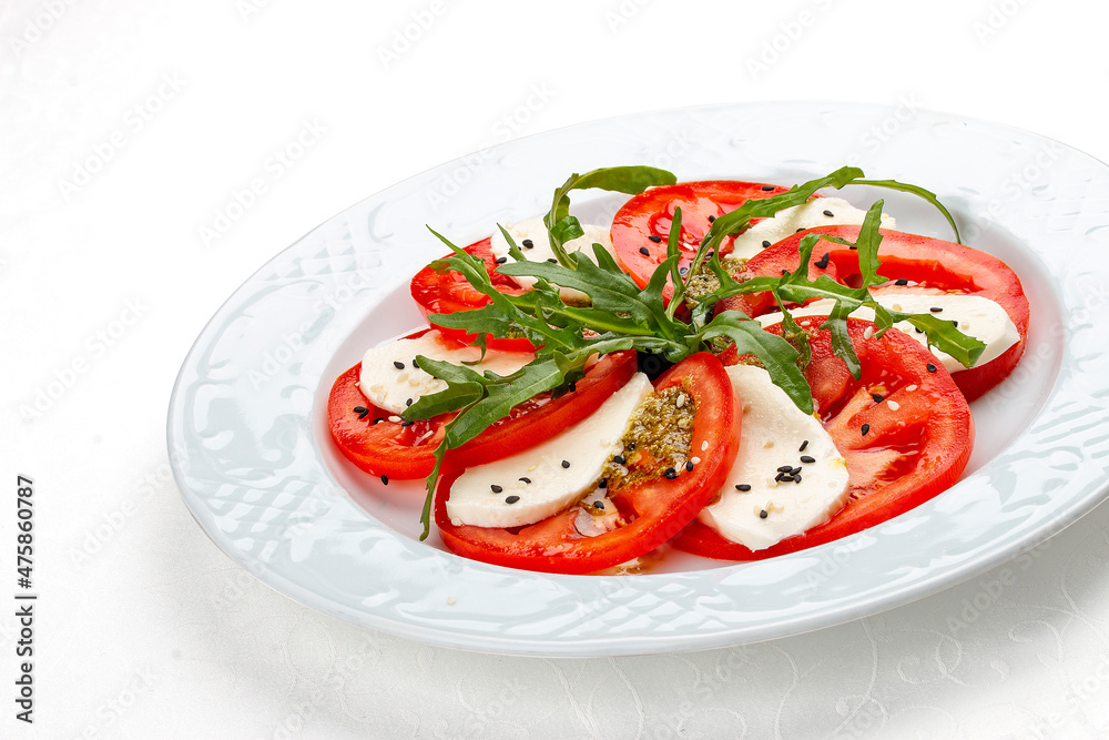 Caprese salad with mozzarella, tomatoes and pesto sauce. A traditional Italian dish. Isolated on a white background.