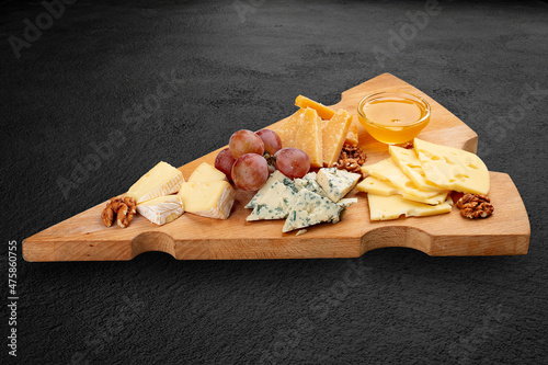 A board with cheese delicacies, walnuts and honey. Isolated on a black background
