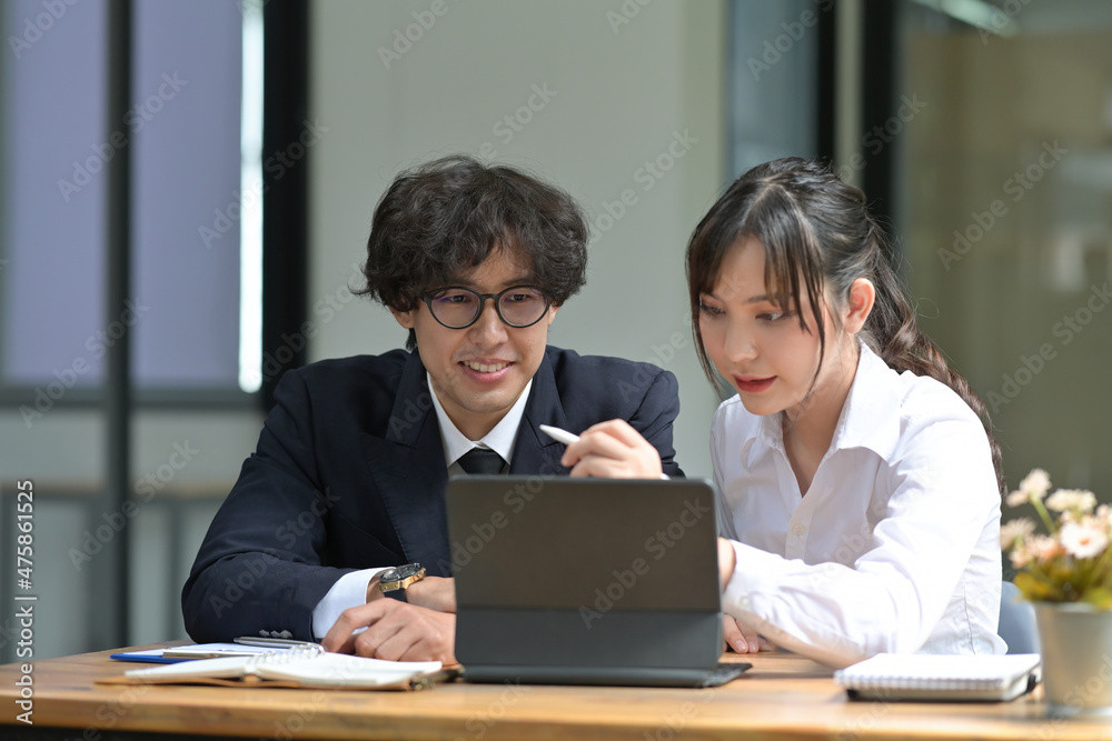Photo of young university students tutoring together with a digital tablet in the university library. Photo of young university students tutoring together with a digital tablet in the university library.