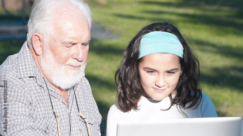 Elderly man explains how to use a laptop to his granddaughter Elderly man explains how to use a laptop to his granddaughter