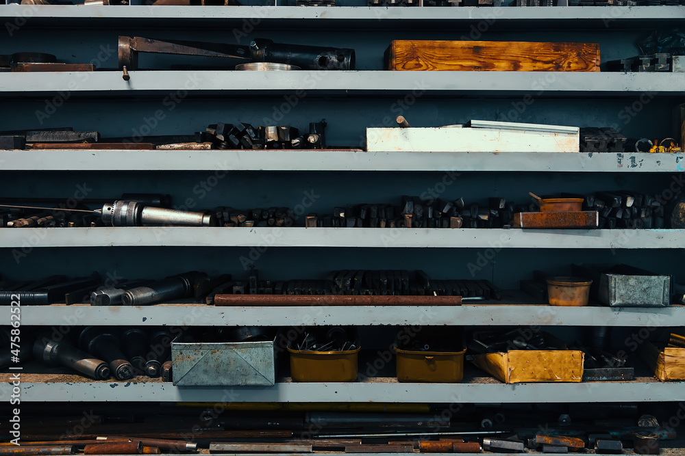 Rack with shelves in lathe shop in factory. On shelves are parts and blanks for working with metal. Industrial background. Length working place of turner. Rack with shelves in lathe shop in factory. On shelves are parts and blanks for working with metal. Industrial background. Length working place of turner.