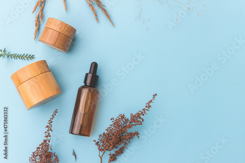 Natural cosmetics on a blue background with a decor of dry herbs. Branding concept. Natural packaging.