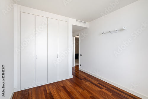 Interior of empty apartment, white room with built-in wardrobe and parquet floor