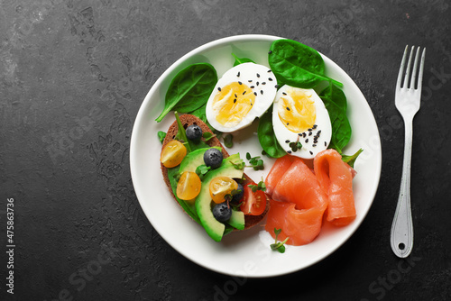 Delicious breakfast, tapas, appetizer. Bread, vegetables, herbs, spinach, eggs, salmon, berries, blueberries. Top view